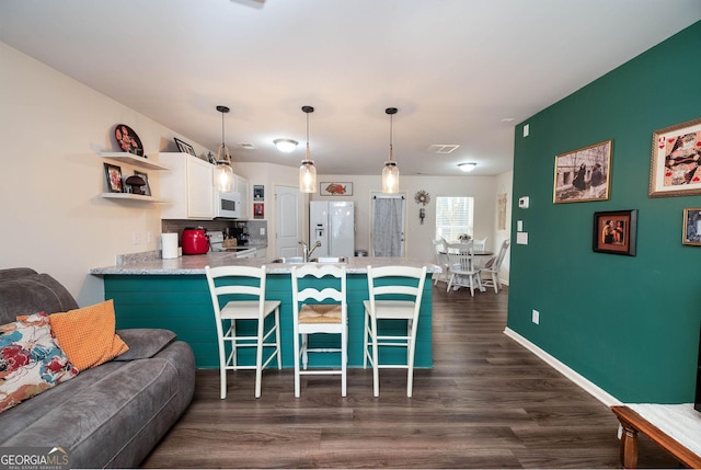 kitchen with a breakfast bar, open shelves, white cabinetry, white appliances, and a peninsula
