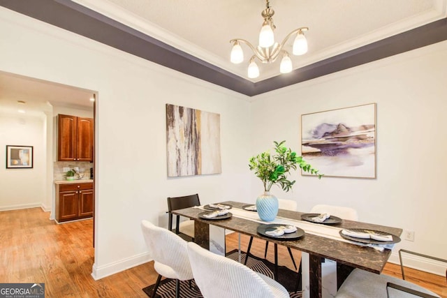 dining room with a notable chandelier, crown molding, and light hardwood / wood-style flooring