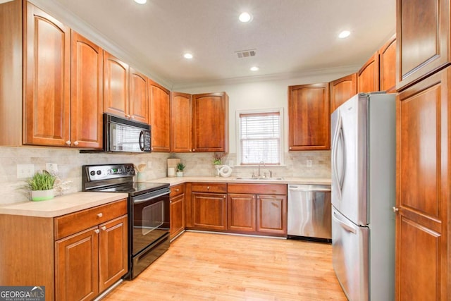 kitchen with decorative backsplash, sink, black appliances, and light hardwood / wood-style floors