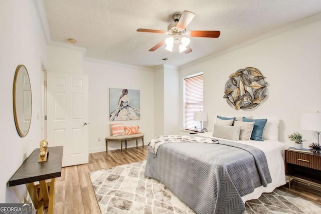 bedroom featuring ceiling fan, wood-type flooring, a textured ceiling, and ornamental molding