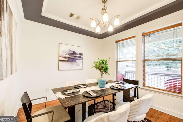 dining area featuring a chandelier, a tray ceiling, hardwood / wood-style flooring, and ornamental molding