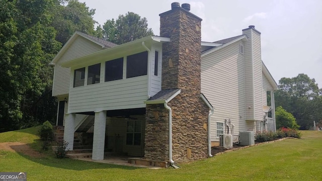 back of house with cooling unit, a patio area, and a lawn