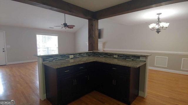 kitchen with light hardwood / wood-style floors, ceiling fan with notable chandelier, lofted ceiling with beams, and kitchen peninsula