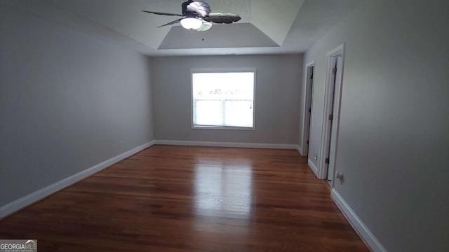 empty room featuring dark hardwood / wood-style floors, ceiling fan, and a raised ceiling