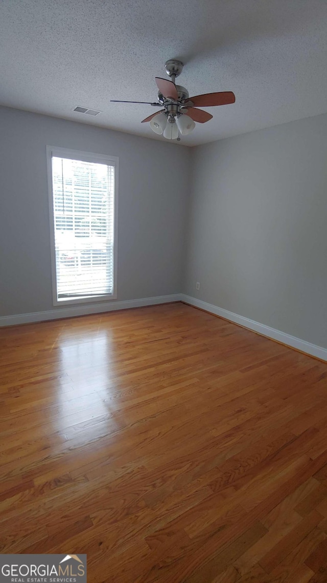 spare room featuring ceiling fan, wood-type flooring, and a textured ceiling