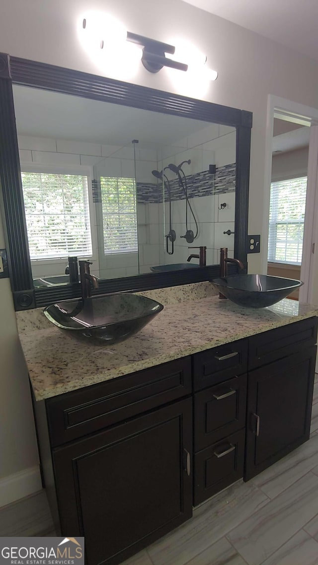 bathroom featuring tiled shower and vanity