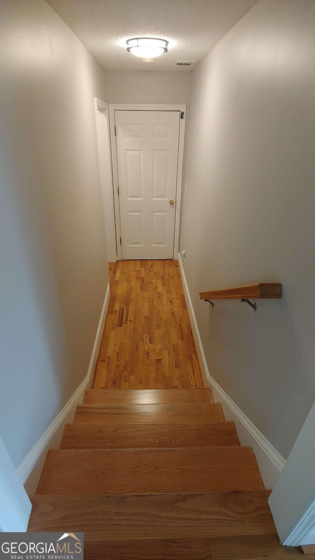 stairway with hardwood / wood-style flooring and a textured ceiling