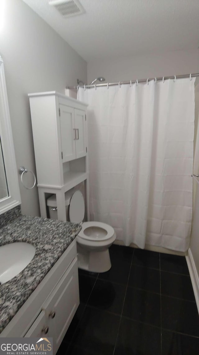 bathroom with a shower with curtain, tile patterned flooring, a textured ceiling, toilet, and vanity