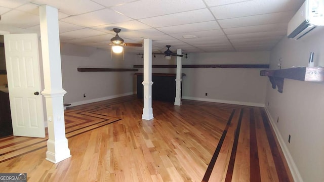 basement with hardwood / wood-style floors, a drop ceiling, and a wall mounted AC