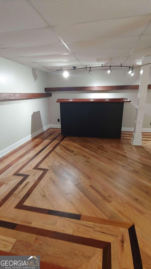 empty room with hardwood / wood-style floors, a paneled ceiling, and track lighting