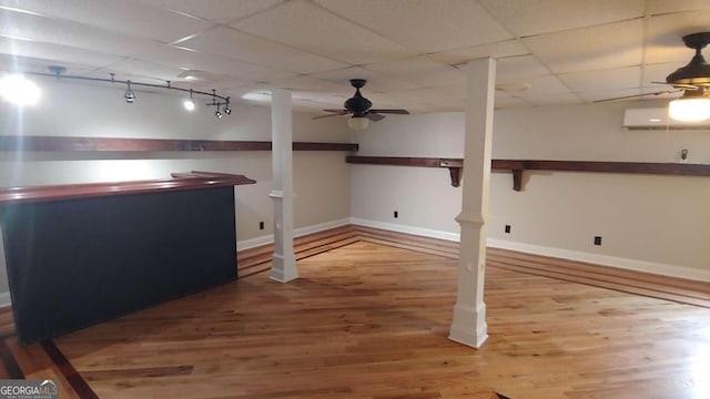 basement with ceiling fan, wood-type flooring, and a wall mounted air conditioner