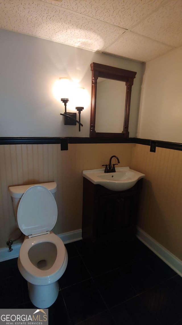 bathroom with tile patterned floors, sink, a drop ceiling, and toilet