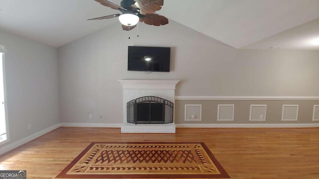 unfurnished living room featuring ceiling fan, wood-type flooring, a fireplace, and vaulted ceiling