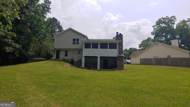 back of property with a sunroom and a yard