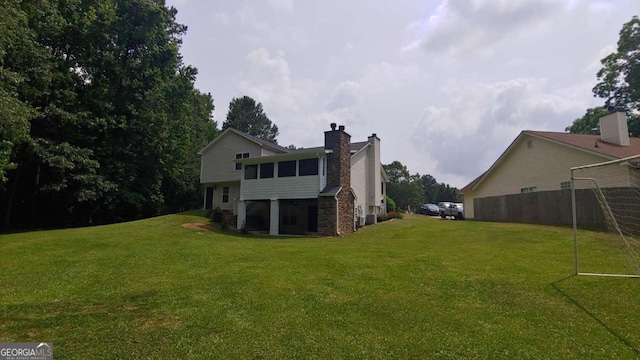 back of house with a sunroom and a lawn