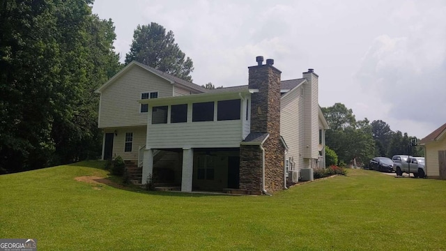 rear view of property featuring a lawn, a sunroom, and central AC unit