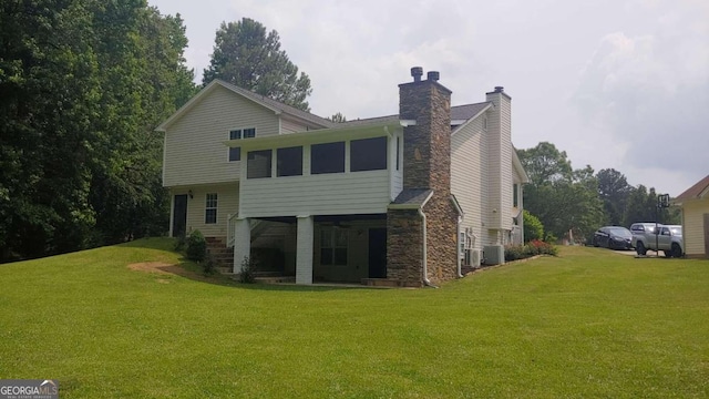 back of house with a lawn, a sunroom, and cooling unit