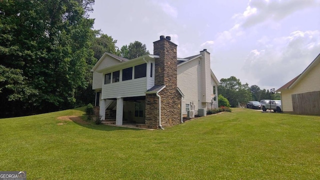 back of property with a sunroom, central air condition unit, and a lawn