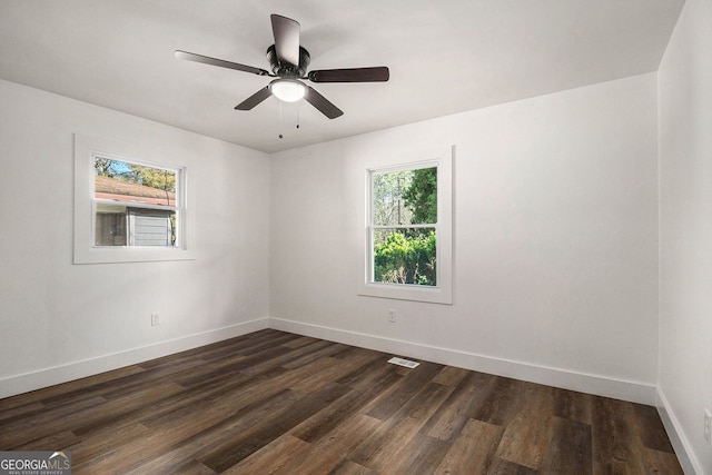 empty room with ceiling fan, a healthy amount of sunlight, and dark hardwood / wood-style flooring