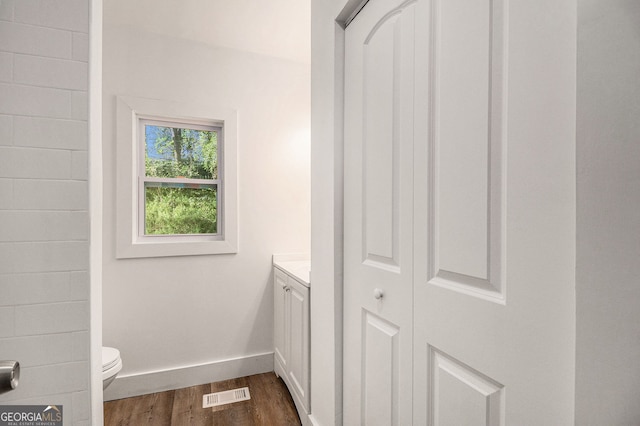 bathroom with wood-type flooring, vanity, and toilet