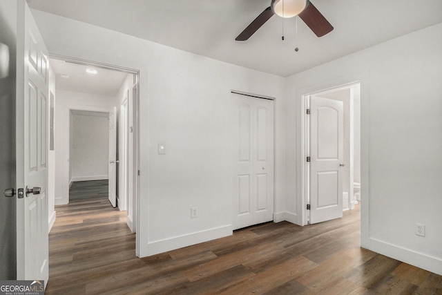 unfurnished bedroom with ceiling fan, dark hardwood / wood-style flooring, and a closet