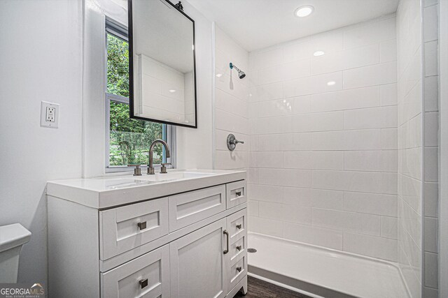 bathroom with vanity, a tile shower, and toilet