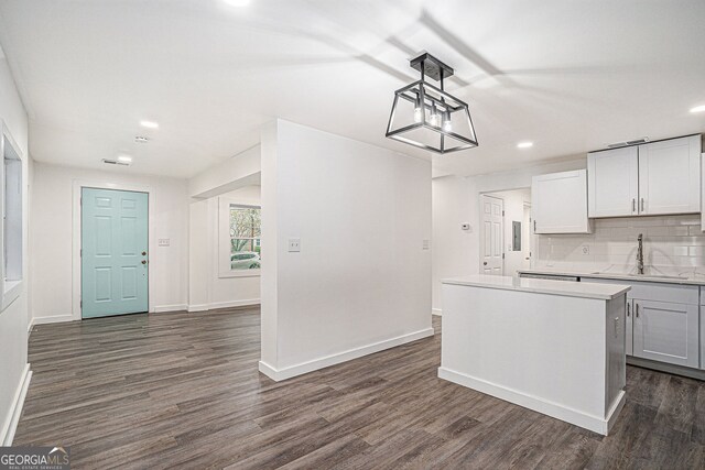 kitchen with sink, white cabinetry, hanging light fixtures, backsplash, and dark hardwood / wood-style floors