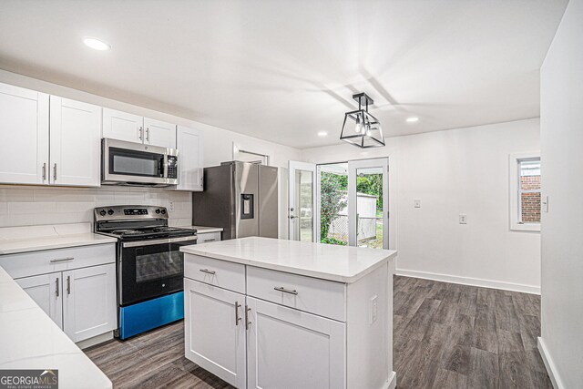 kitchen with hanging light fixtures, backsplash, stainless steel appliances, dark hardwood / wood-style floors, and white cabinets