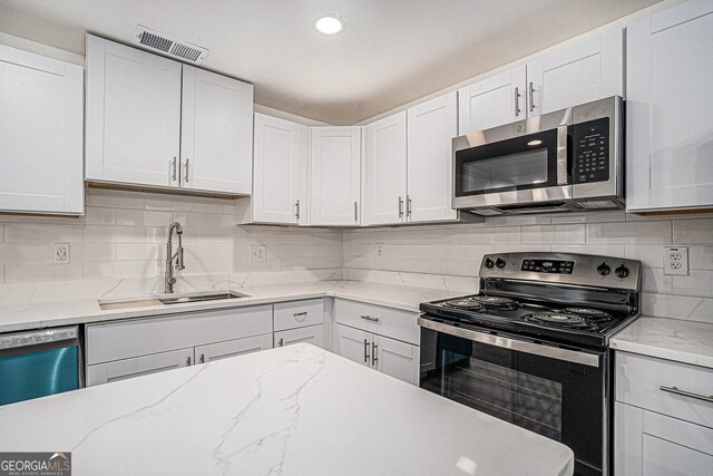 kitchen featuring white cabinetry, sink, backsplash, and stainless steel appliances