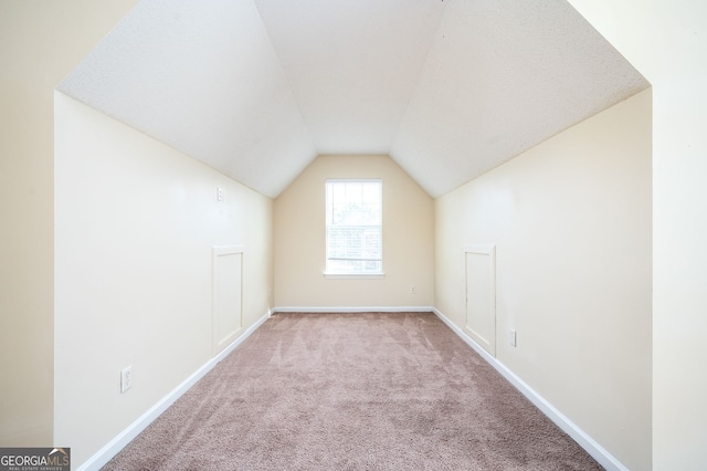 additional living space featuring light carpet and vaulted ceiling