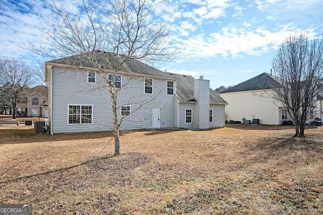 rear view of property with central AC unit and a lawn