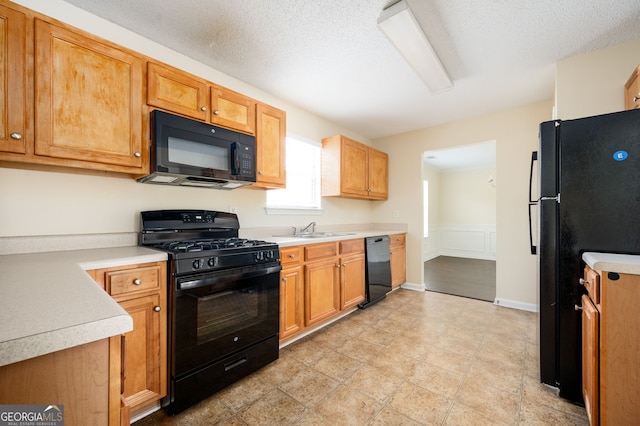 kitchen featuring a textured ceiling, sink, and black appliances