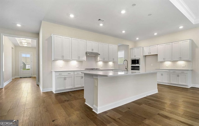 kitchen with white cabinets, a kitchen island with sink, and built in microwave