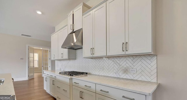 kitchen featuring white cabinets, light stone countertops, and stainless steel gas cooktop