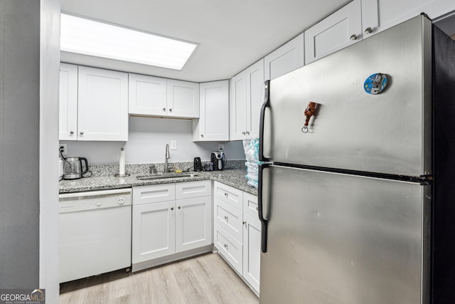 kitchen with stainless steel refrigerator, light stone countertops, dishwasher, sink, and white cabinets