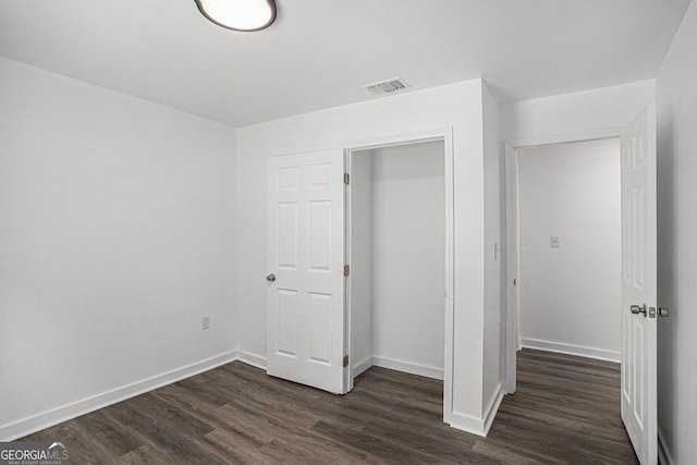 unfurnished bedroom featuring dark hardwood / wood-style flooring and a closet