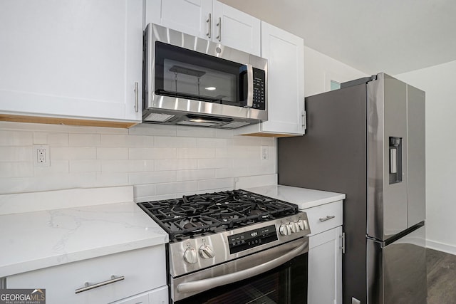 kitchen featuring white cabinetry, appliances with stainless steel finishes, backsplash, and light stone counters