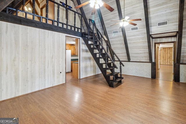 unfurnished living room with visible vents, beamed ceiling, stairway, and wood finished floors