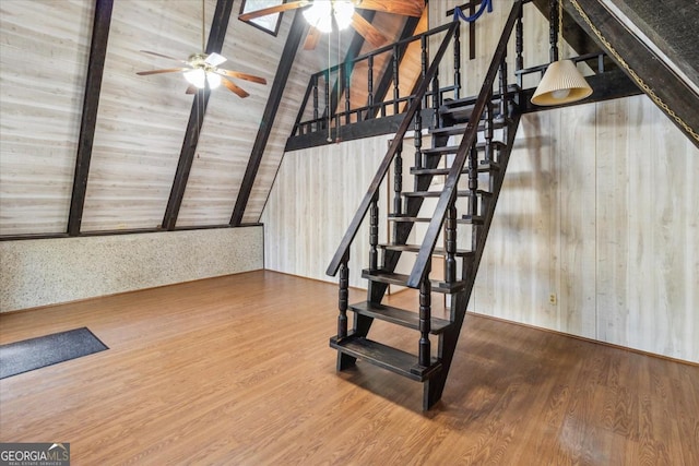 stairs featuring a ceiling fan, vaulted ceiling with beams, and wood finished floors