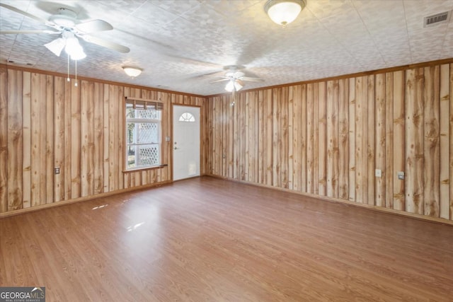 unfurnished room with ceiling fan, visible vents, crown molding, and wood finished floors