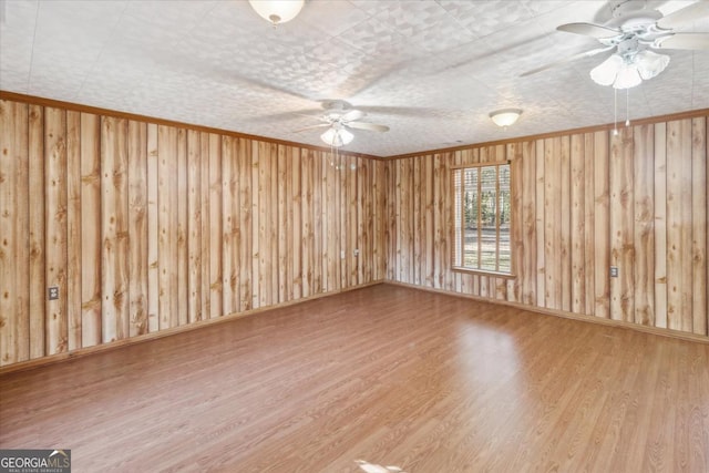 spare room with ceiling fan, crown molding, baseboards, and wood finished floors