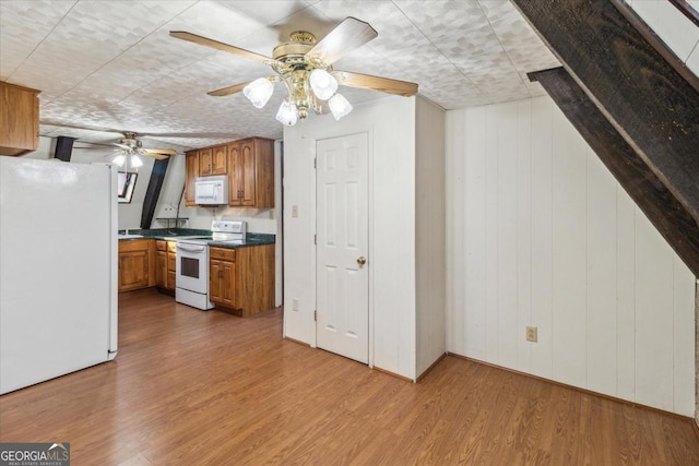 kitchen featuring white appliances, dark countertops, wood finished floors, and brown cabinets