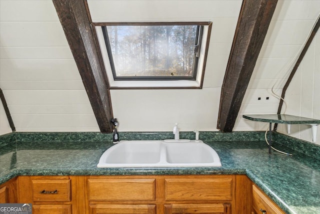 bathroom with lofted ceiling with beams, a sink, and a bathing tub