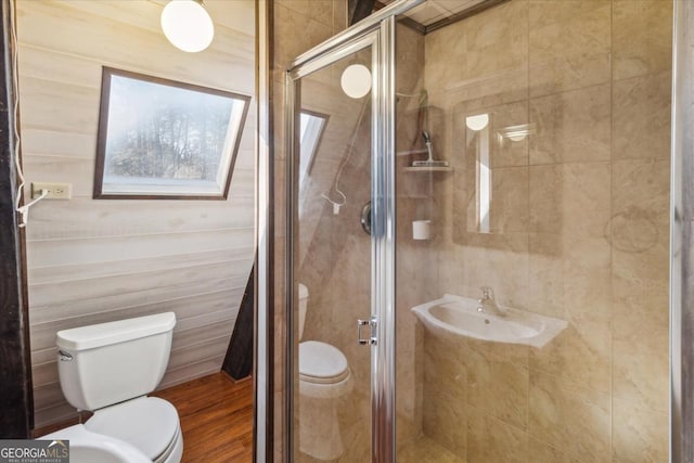 full bath featuring wood finished floors, a sink, toilet, and a shower stall