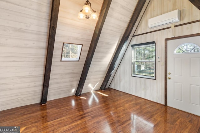 entryway with a wall unit AC, vaulted ceiling with beams, wooden walls, wood finished floors, and a chandelier