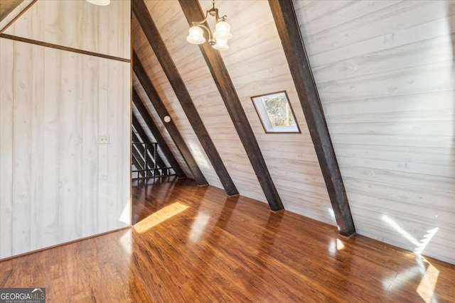 interior space with wooden walls, lofted ceiling with beams, wooden ceiling, wood finished floors, and a chandelier