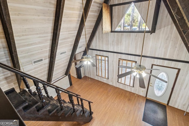 stairs with ceiling fan, visible vents, beamed ceiling, and wood finished floors