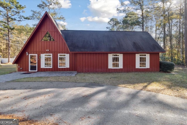 exterior space featuring roof with shingles and a front lawn