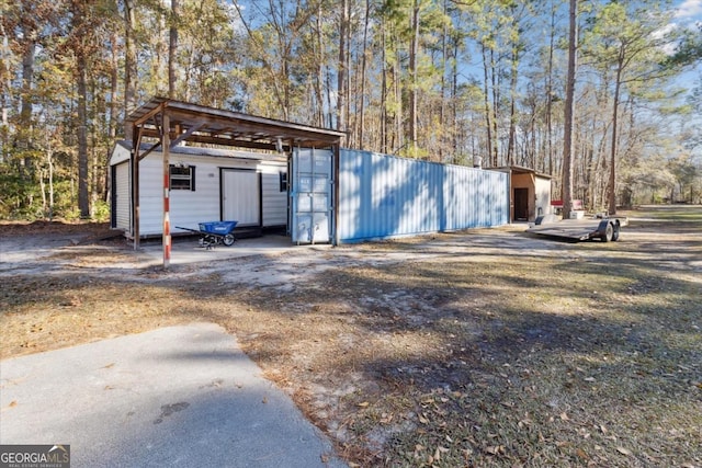 view of outdoor structure featuring an outbuilding, a carport, and a wooded view