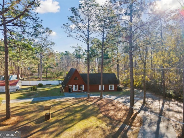 view of front of home with fence, a view of trees, and a front yard